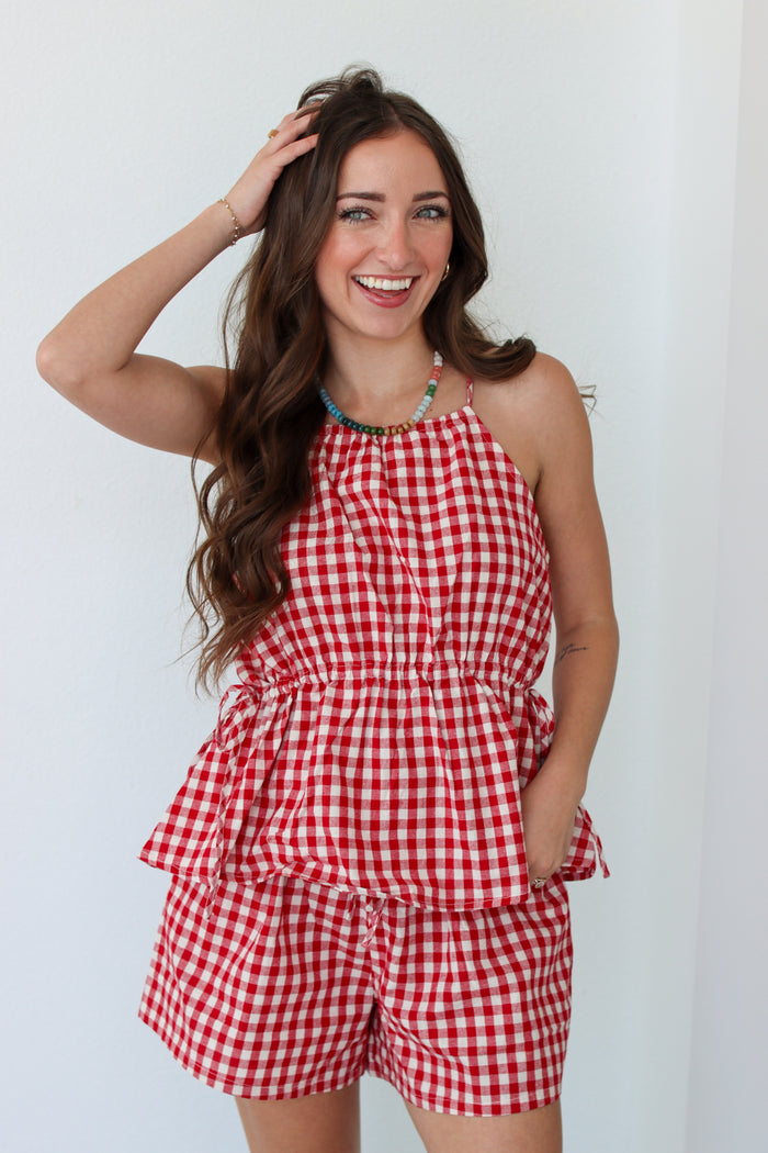 Woman wearing a red gingham shorts set against a white background