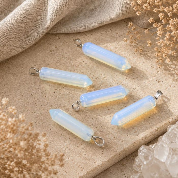Opalite crystal point pendants with silver loops on a neutral stone background.