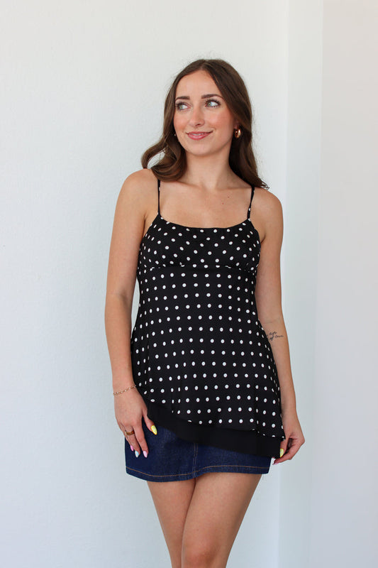 Woman wearing a black polka dot top with a denim mini skort