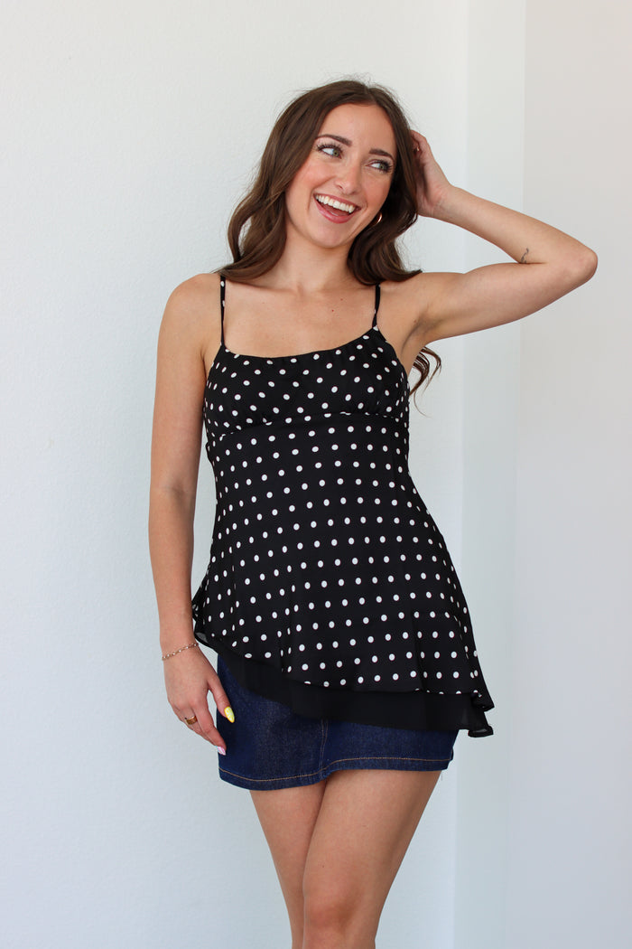 Woman wearing a black polka dot top with a denim mini skort