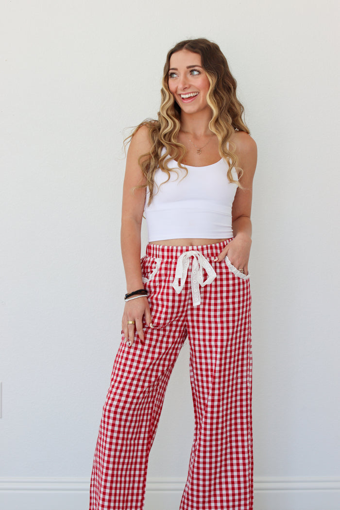 Woman wearing a white top and red gingham pants against a white background