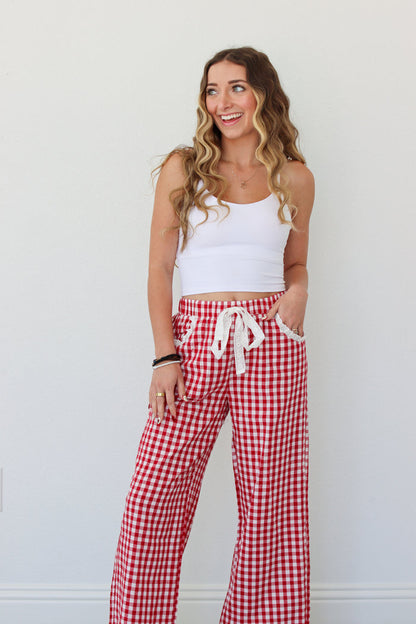 Woman wearing a white top and red gingham pants against a white background