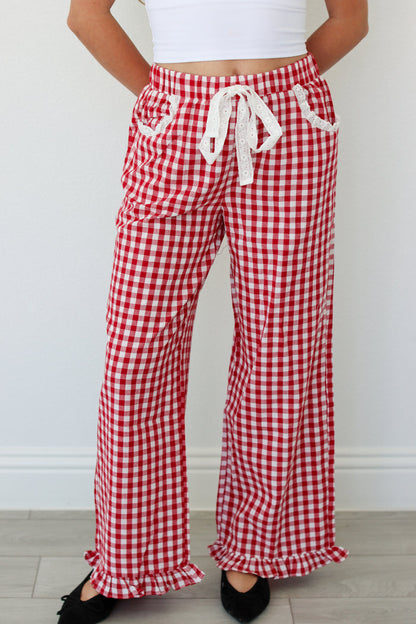 Red and white gingham pants with ruffles worn by a person on a plain background