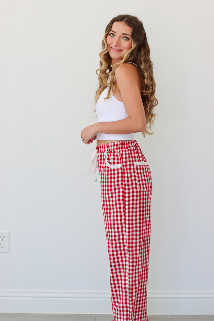 Woman wearing a white top and red gingham pants against a white background