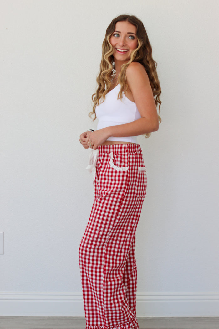 Woman wearing a white top and red gingham pants against a white background