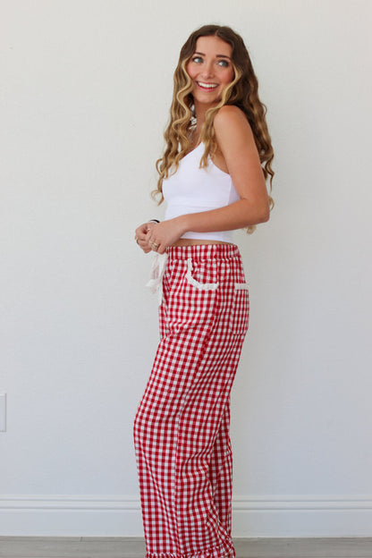 Woman wearing a white top and red gingham pants against a white background
