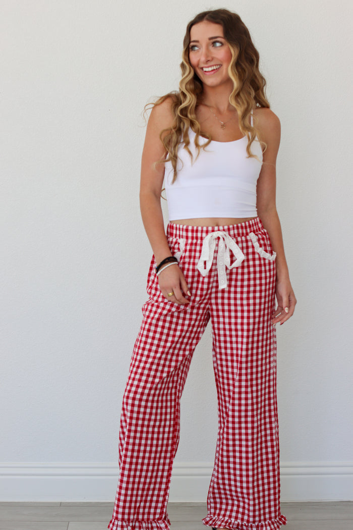Woman wearing a white top and red gingham pants against a white background