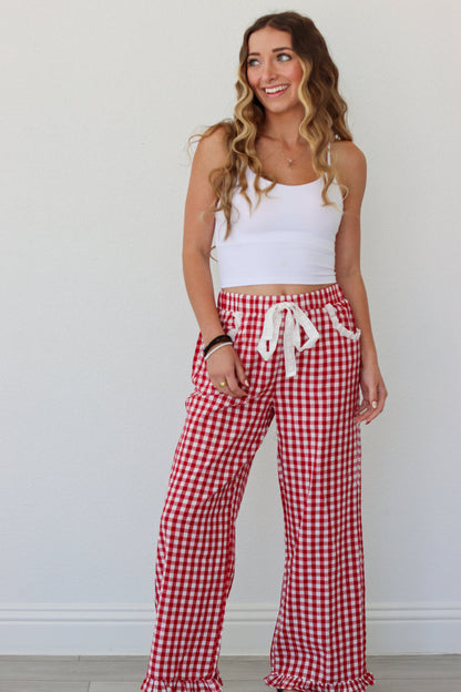 Woman wearing a white top and red gingham pants against a white background