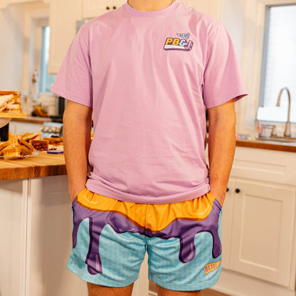 Male model wearing BL101 PB&J mesh shorts and a pink BL101 PB&J tee in a kitchen setting.