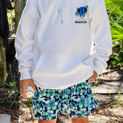Person wearing a white hoodie with a floral BL101 logo and 'Swing into Spring Beach Club' text and floral shorts holding a baseball.