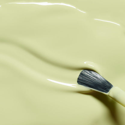 A paintbrush lies on the smooth, glossy surface of Manucurist’s Pistachio—a light yellow-green shade with gentle waves—evoking the soft pastel look of this LED Gel polish.