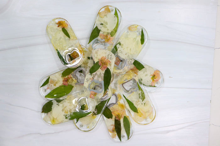 Landscape photo of a pressed flower bottle opener with dried flowers in a resin handle