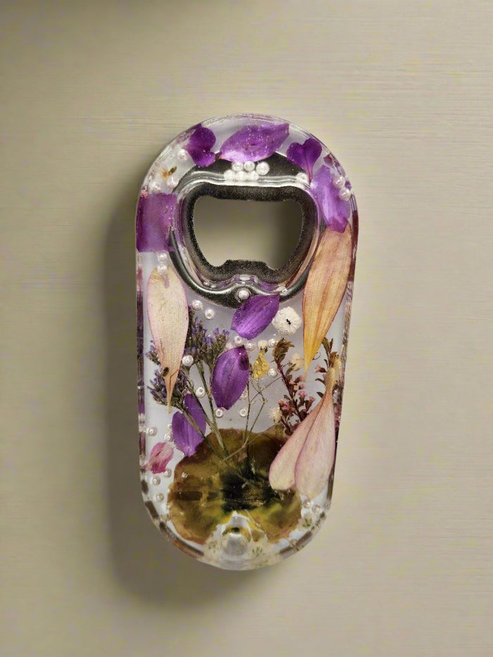 Pressed flower bottle opener with dried flowers set on a beige background