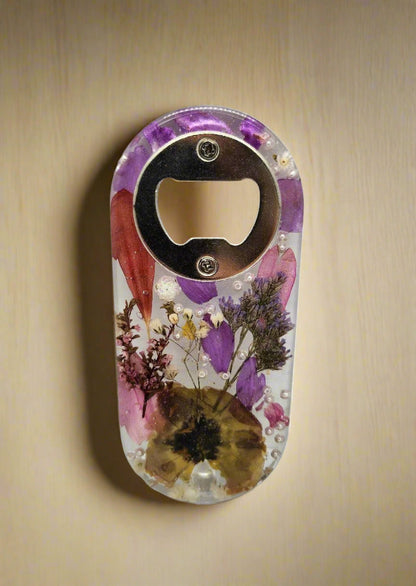 Pressed flower bottle opener with dried flowers set on a wood background