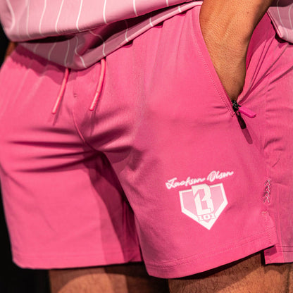 Close-up of the pink Pro Series Shorts V2 showing the "Jackson Olson" script, BL101 home plate logo, zip pocket, and chevron detail