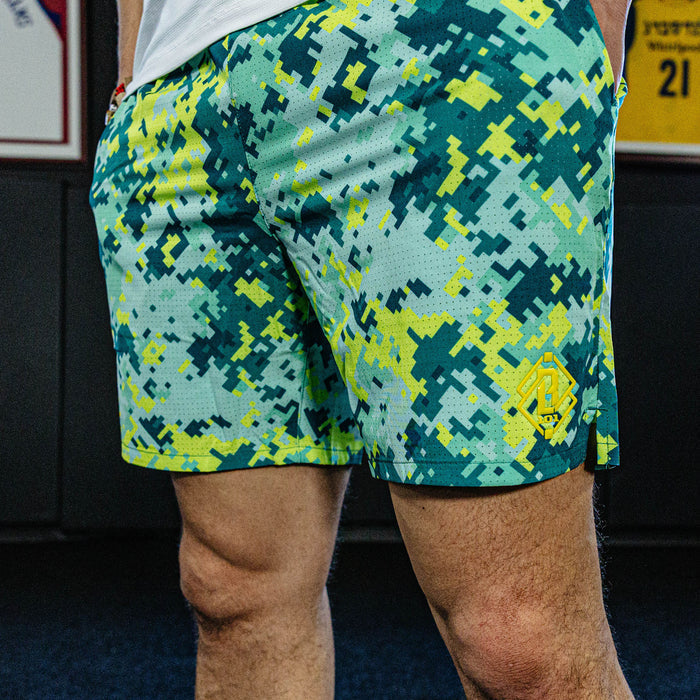Person wearing green and blue camouflage shorts with a blurred background