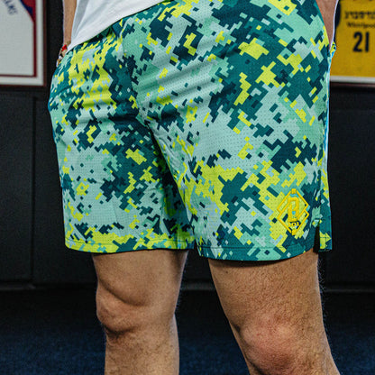 Person wearing green and blue camouflage shorts with a blurred background