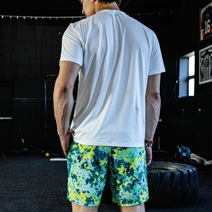 Person wearing a white t-shirt and colorful shorts in a gym setting
