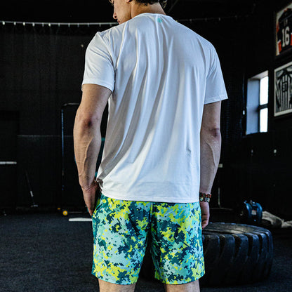 Person wearing a white t-shirt and colorful shorts in a gym setting