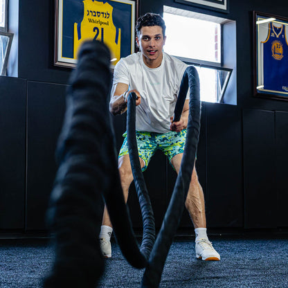 Man using battle ropes in a room with colorful shorts