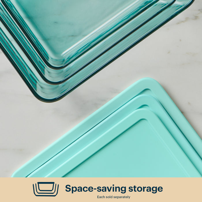 Stack of teal glass storage containers on a light gray surface with 'Space-saving storage' text at the bottom.