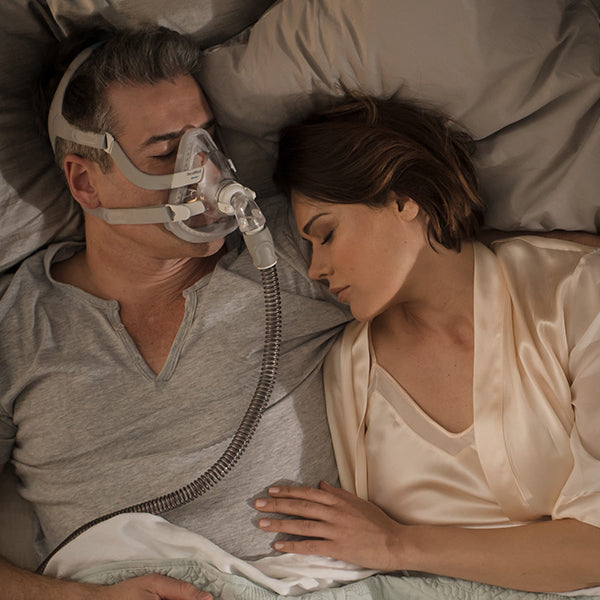 Man in bed wearing a Full Face CPAP Mask with a Resmed Quietair Elbow