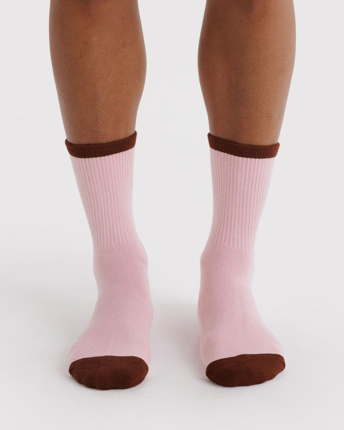 Ribbed blush pink socks on feet with dark brown cuff and rounded toe.