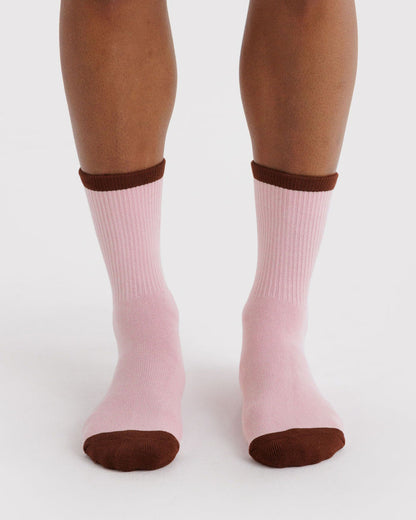 Ribbed blush pink socks on feet with dark brown cuff and rounded toe.