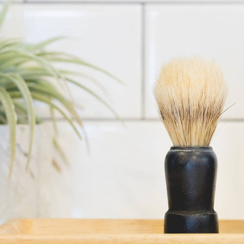 The Immaculate Beard shaving brush with natural bristles and a sleek handle for a traditional shaving experience.