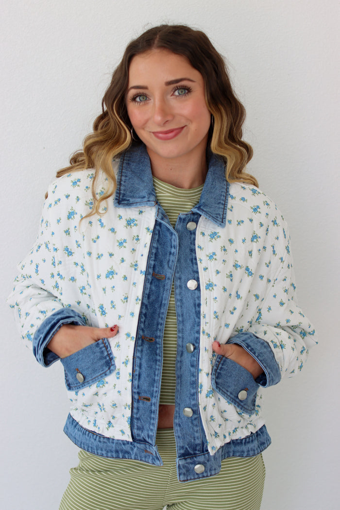 Woman wearing a floral denim jacket with a white background