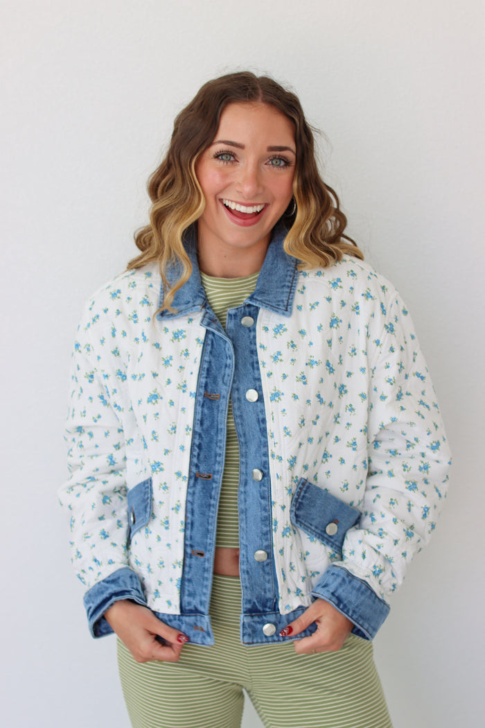 Woman wearing a floral denim jacket with a white background