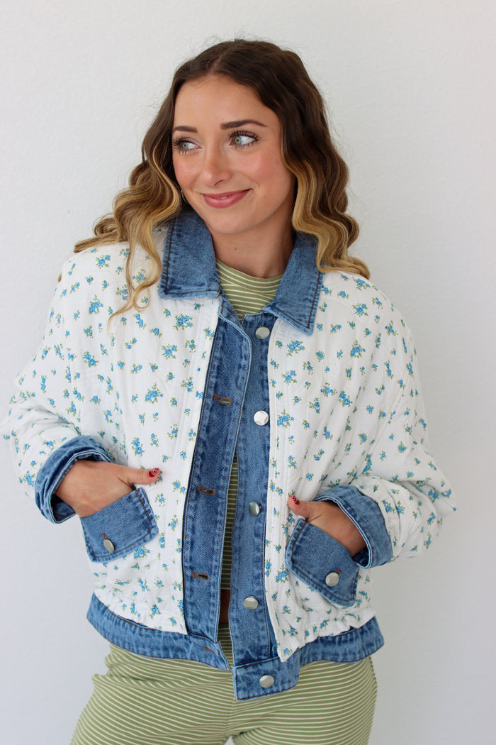 Woman wearing a floral denim jacket with a white background