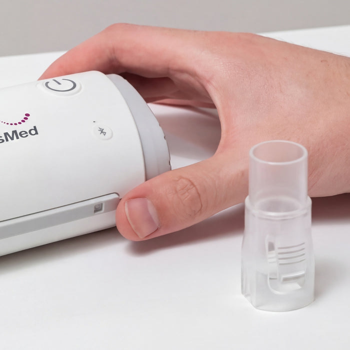 Hand holding a CPAP device next to a CPAP hose connector