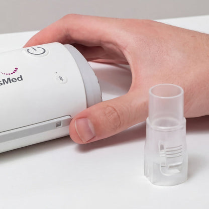 Hand holding a CPAP device next to a CPAP hose connector