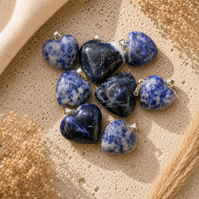 Sodalite heart crystal pendants with silver bails on a neutral textured background.