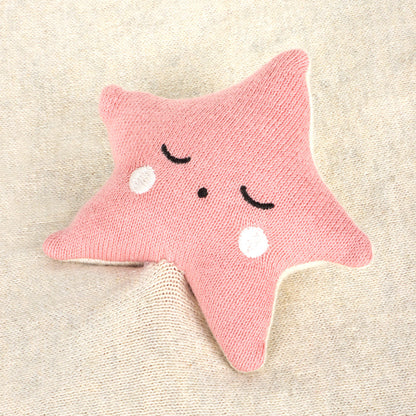 Pink star-shaped toy with a smiling face on a beige background