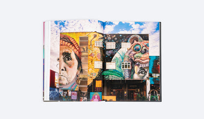 Open photo art book spread with colorful city building murals and faces