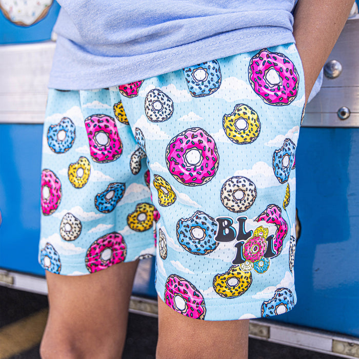 Youth model wearing multi-color youth shorts with “Sugar Rush Donut” design