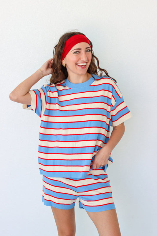 Woman wearing a blue and red striped outfit with a headband against a white background