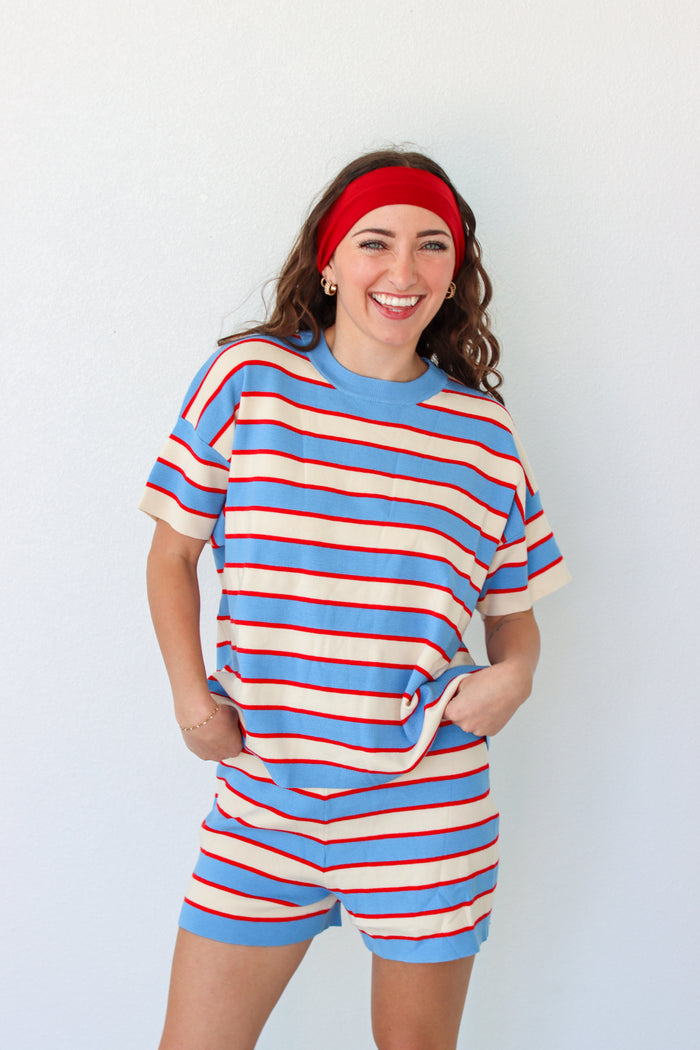 Woman wearing a blue and red striped outfit with a headband against a white background