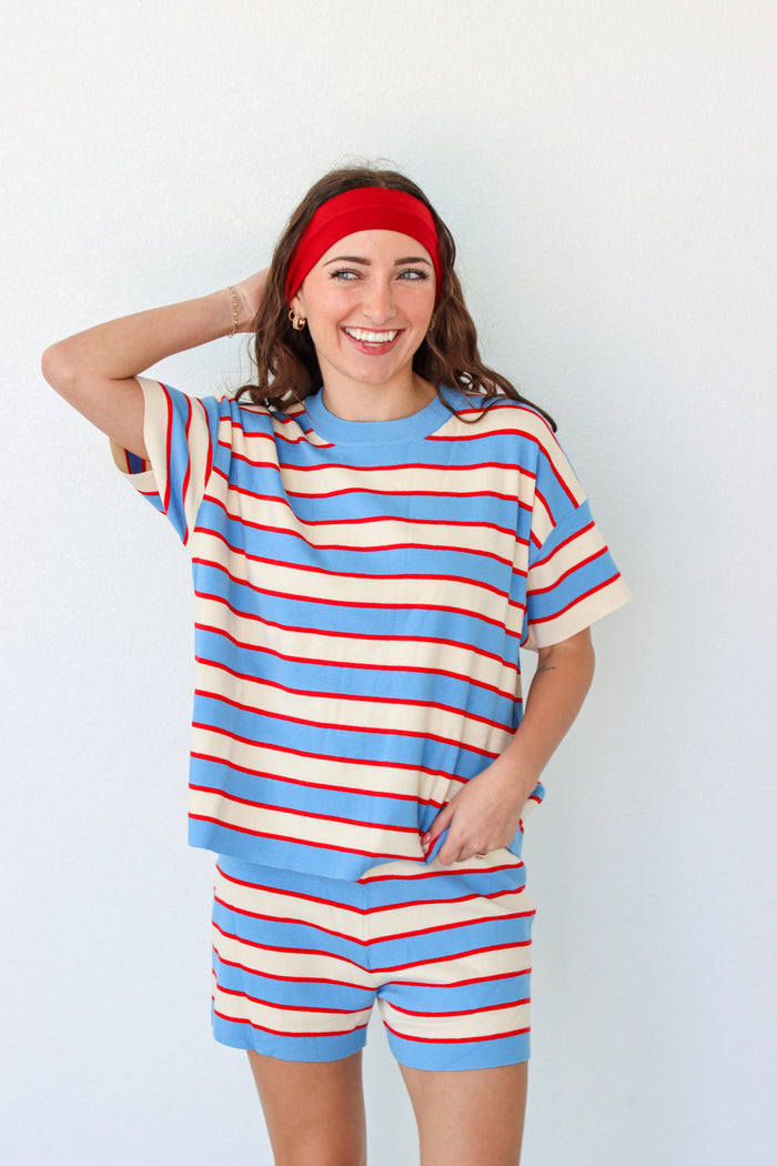 Woman wearing a blue and red striped outfit with a headband against a white background