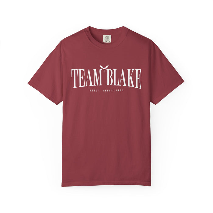 Bloodwing Academy Comfort Colors graphic tee by thtgrlreads in vintage wash maroon with white "Team Blake" text and a small flying bird graphic, part of official romance fandom merch.