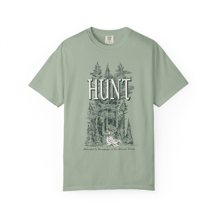 Thtgrlreads The Poison Daughter collection features a sage green Comfort Colors graphic tee with vintage wash and a detailed forest scene surrounding the large "HUNT" text in a classic font.