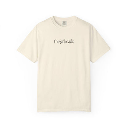 Thtgrlreads bookish apparel featuring a vintage wash Comfort Colors cream graphic tee with minimalist black serif text "thisgrlreads," part of the Tees and Book Bestie collections.
