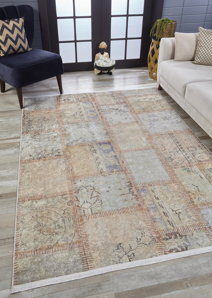 A modern living room features the Urban Utopia - Washable Rug - JR1957 in cream and beige on a light wood floor, paired with a dark blue chair with a chevron pillow, white sofa, potted plant, and double frosted glass doors.