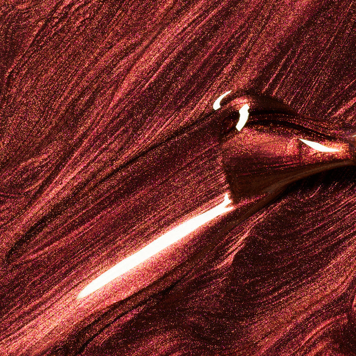 Close-up of Manucurist's Utopia, a shimmering metallic burgundy gel polish, being brushed on for smooth, reflective waves—perfect for fans of glossy, metallic finishes.