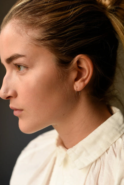 Gold-tone wishbone threader earrings on ear, thin wire with dangling bar
